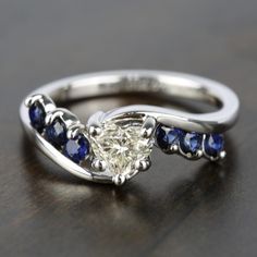 a diamond and blue sapphire engagement ring on a table with wood grained surface in the background