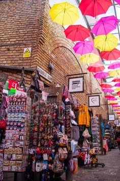 there are many umbrellas hanging from the ceiling in this market place that is filled with merchandise