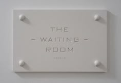 the waiting room sign is mounted to the wall with three white knobs on it