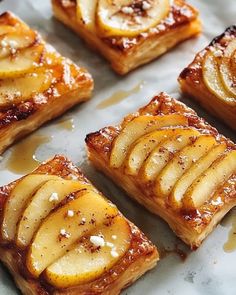 several pieces of pastry with bananas and other toppings on top of each one, sitting on a piece of parchment paper