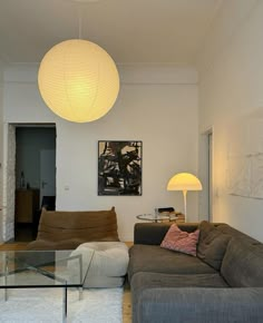 a living room filled with furniture and a large white light hanging over the top of it