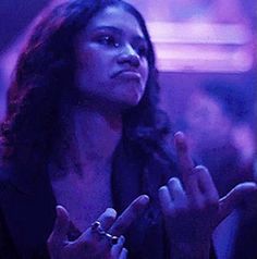 a woman standing in front of a crowd with her hands together