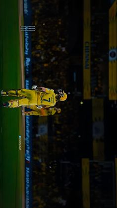 a yellow race car is reflected in the wet ground at night time, with lights reflecting on it's surface