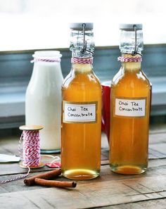 two glass bottles filled with liquid sitting on top of a wooden table next to some cinnamon sticks