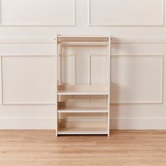 an empty shelf against a white wall with wood flooring