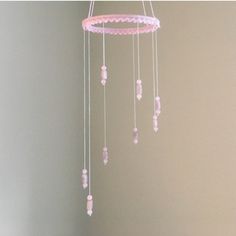 a baby crib mobile with pink beads hanging from it's sides in a room