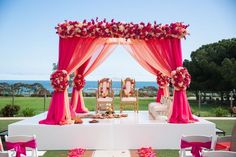 an outdoor wedding setup with pink and red flowers