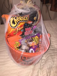 an orange basket filled with candy on top of a bed