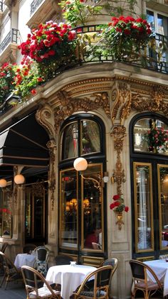 an outdoor restaurant with flowers on the balcony