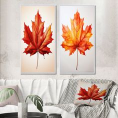 two red and orange maple leaves hanging on a wall above a white couch in a living room