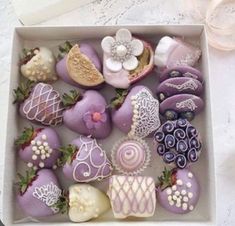 a box filled with lots of different types of decorated chocolates on top of a table