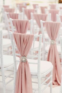 rows of white chairs with pink sashes on them