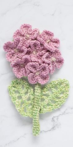 two crocheted flowers sitting on top of a white table