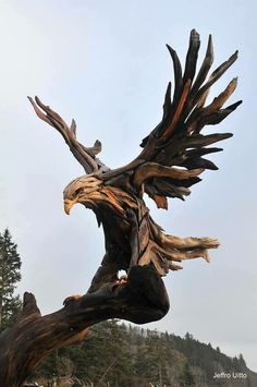 an eagle statue sitting on top of a tree branch