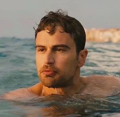 a man is swimming in the ocean with his head turned to the side and looking at the camera