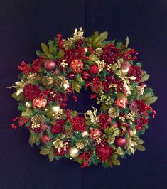 a christmas wreath with pomegranates and greenery hanging on a wall