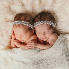 two newborn babies are sleeping together on a white blanket with their heads wrapped around each other