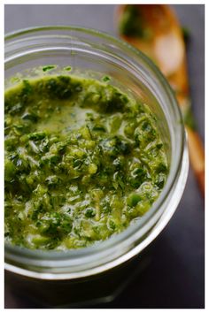 a glass jar filled with green sauce on top of a blue and yellow table cloth