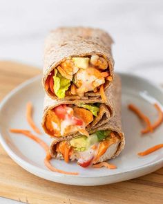 a burrito cut in half on a plate with carrots and lettuce