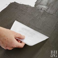 a person is using a sponge to paint a wall with gray and white colors on it