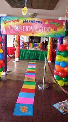 an indoor party with balloons and streamers on the floor, decorated in rainbow colors