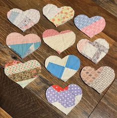 several heart shaped pieces laid out on a wooden table with different patterns and colors to make them look like they are made from fabric