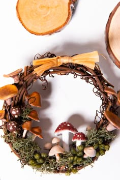 a wreath with mushrooms, moss and other things around it on a white table top