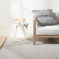 two glasses of orange juice sit on a table in front of a couch with pillows