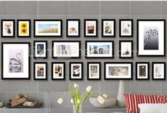 a living room filled with lots of framed pictures on the wall above a couch and coffee table