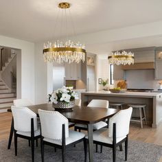 a dining room table with white chairs and chandelier