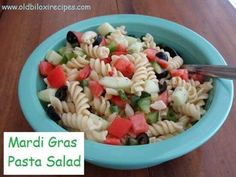 a blue bowl filled with pasta salad on top of a wooden table