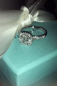 a diamond engagement ring sitting on top of a blue box with a white ribbon around it