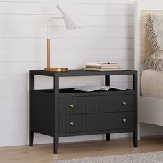 a night stand with two drawers and a lamp next to it on a wooden floor