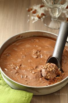 a spoon in a pan filled with chocolate ice cream on top of a wooden table