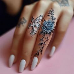 a woman's hand with tattoos on it and a rose tattoo on the middle finger