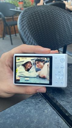 a person holding up a cell phone to take a picture with their friends on the screen