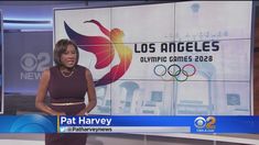 a news anchor is standing in front of the los angeles olympics logo