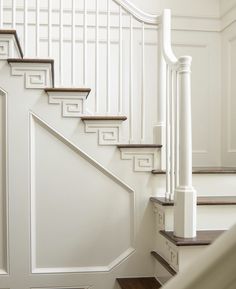 a white staircase with wooden handrails and rails