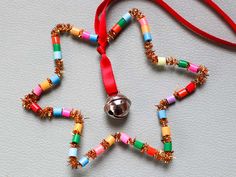 a colorful beaded star ornament hanging from a red ribbon on a white surface