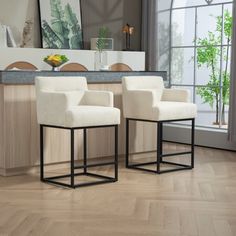 two white chairs sitting on top of a hard wood floor next to a kitchen counter