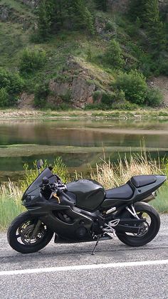 a motorcycle is parked on the side of the road next to some grass and water