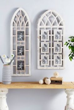 two white vases sitting on top of a wooden table next to an arched window