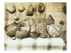 several baskets are sitting on a table with hats hanging from the wall behind them in black and white