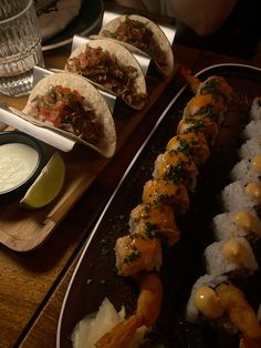 several different types of sushi on plates with dipping sauces and lime wedges