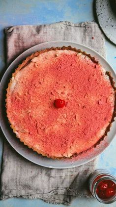 there is a pie on the table with a cherry on it and some sauce next to it