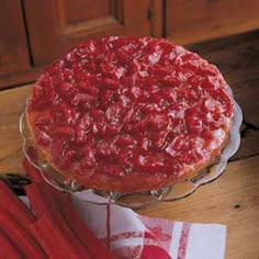 there is a large cake on top of a glass stand with red icing and sprinkles