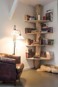 a living room filled with furniture and bookshelves next to a wall mounted lamp