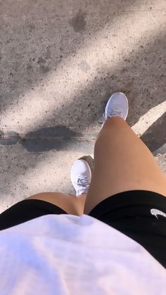 a person laying on the ground with their feet up in front of them, wearing white sneakers