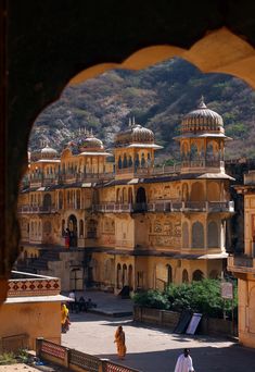 people are walking around in front of an old building with many domes on it's sides