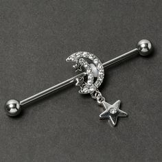 a star and moon belly button bar with crystal stones on it's end, sitting on a black surface